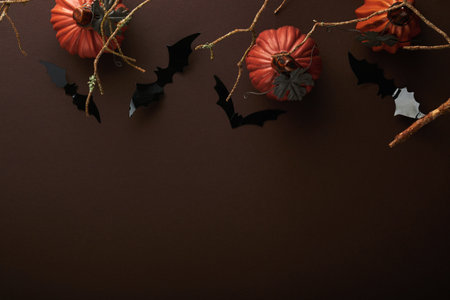 Halloween background. Flock of black bats, spider, pumpkin, skeleton and leaves for Halloween. Black paper bat silhouettes on brown or dark background. autumn decoration. Halloween concept. top view.の写真素材
