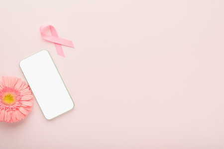 Pink Breast Cancer Awareness Ribbon. Gerbera and pink ribbon and white phone backgrounds. Breast cancer awareness and October Pink day, world cancer day. top view. Mock up.の写真素材