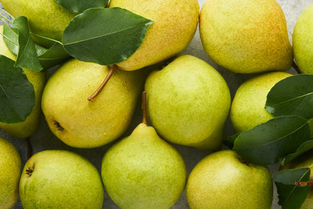 Pears. Fresh sweet organic pears with leaves in wooden box or basket on old stone tile background....