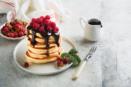 american pancakes. Stack pancakes with fresh raspberry with chocolate glaze or toppings in white bowl on light gray table background. Homemade classic american pancakes. magazine concept. top view.の写真素材