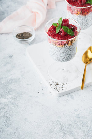 Chia pudding. Healthy vanilla chia pudding in glass with fresh raspberries and mint on white background. Vegan healthy breakfast.の写真素材