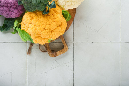 Colorful cauliflower. Various sort of cauliflower on stone tiles gray concrete background. Purple, yellow, white and green color cabbages. Broccoli and Romanesco. agricultural harvest. Mock up.の写真素材