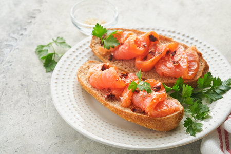 Sandwiches with salted salmon. Open sandwiches from cereal or whole grain rye bread with salted salmon, sesame seeds and dried tomato on white marble stand. Seafood. Healthy food. Scandinavian cuisineの写真素材