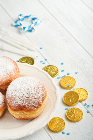 Happy Hanukkah. Hanukkah sweet doughnuts, gift boxes, white candles and chocolate coins on white wooden background. Image and concept of jewish holiday Hanukkah. Top view.の写真素材