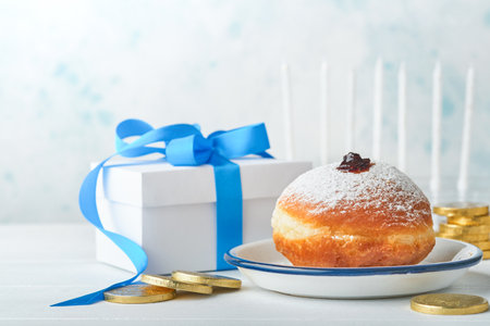 Happy Hanukkah. Hanukkah sweet doughnuts, gift boxes, white candles and chocolate coins on white wooden background. Image and concept of jewish holiday Hanukkah. Top view.の写真素材
