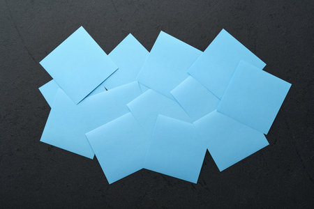 Blue paper stickers on black background. Sticky notes blank with copy space ready for your message. New year goals or resolutions concept. Blue Monday idea. Flat lay copy space on black background.の写真素材