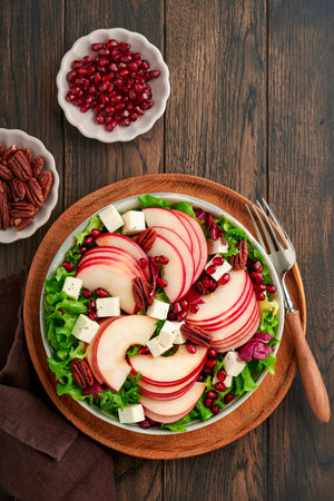 Salad. Fresh fruit green salad with feta cheese, apple, pomegranate, pecan and lettuce on white plate. Idea for healthy delicious winter Christmas salad. Healthy balanced eating. top view.の写真素材
