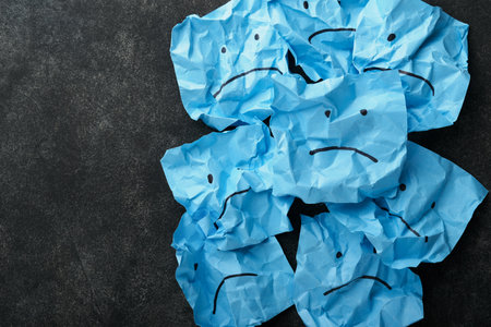 Blue crumpled sticky notes blank with drawing sad face on black background with copy space ready for your message. Blue Monday and mental health concept idea. Flat lay copy space on black background.の写真素材