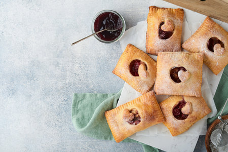 Valentines day heart shaped Hand pies. Mini puff pastry or hand pies stuffed with apple and sprinkle sugar powder in plate. Idea for homemade romantic snack Valentines day. top view. copyspace.の写真素材