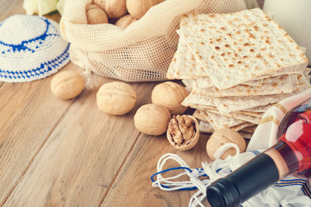 Passover celebration concept. Matzah, red kosher and walnut. Traditional ritual Jewish bread matzah, kippah and tallit on old wooden background. Passover food. Pesach Jewish holiday. toned image.の写真素材