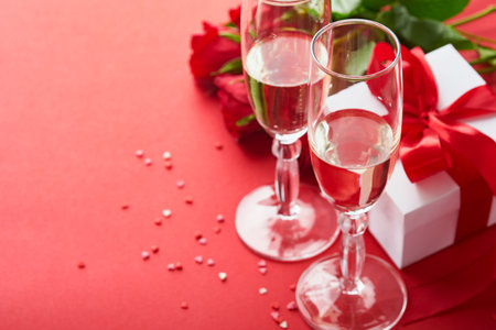 Valentines Day or Romantic dinner concept. Romantic table setting, silverware, wine glasses, gift box, roses and symbol of love red heart on red background. Romantic Dinner Valentines Day concept.の写真素材
