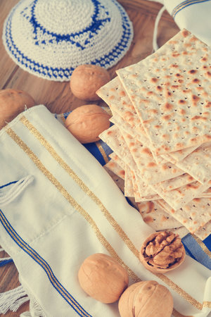 Passover celebration concept. Matzah, red kosher and walnut. Traditional ritual Jewish bread matzah, kippah and tallit on old wooden background. Passover food. Pesach Jewish holiday. toned image.の写真素材