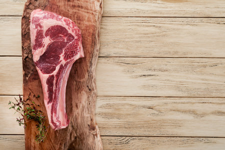 Fresh tomahawk raw steak. Dry aged raw tomahawk beef steak with herbs and salt on old wooden background. Preparing to grill. Top view and copy space.の写真素材