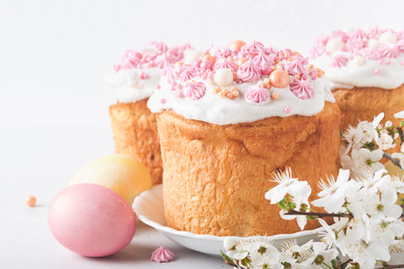 Traditional Easter sweet bread or cakes with white icing and sugar decor, colored eggs and cherry...