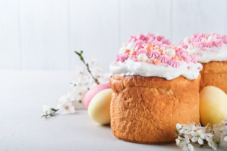 Traditional Easter sweet bread or cakes with white icing and sugar decor, colored eggs and cherry...