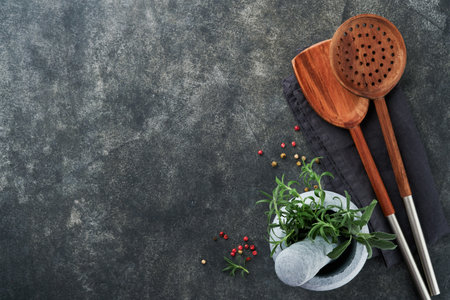 Fresh Rosemary and saffron in marble mortar and wooden spoons on black stone background. food...