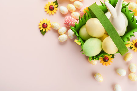 Happy Easter. Easter eggs and rabbit in green basket on pink background with white and yellow roses....