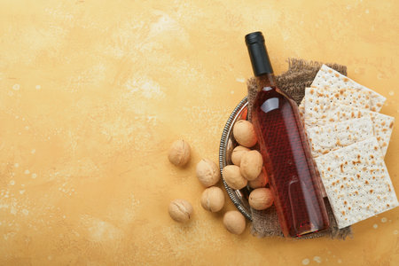 Passover Pesah celebration concept. Matzah, kosher red wine, walnut and white and yellow roses. Traditional ritual Jewish bread on sand color old tile wall background. Pesach Jewish holiday. top viewの写真素材