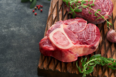 Osso Buco raw steak meat. Barbecue meat. Raw fresh cross cut veal shank and seasonings pepper, rosemary, thyme and salt on old wooden rustic background. Beef Leg Slice with marrow. Italian menu.の写真素材