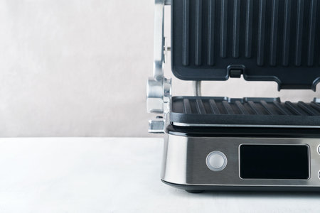 electric grill. Modern kitchen portable grill tool for modern kitchen for grilling meat, vegetables and snacks for dinner or party on light gray background. Place for text or advertisement. Mock up.の写真素材