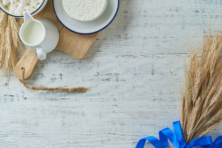 Shavuot jewish holiday celebration. Kosher fresh dairy products milk and cheese, ripe wheat, cream on white wooden background. Dairy products over white wooden background. Shavuot concept. top view.の写真素材