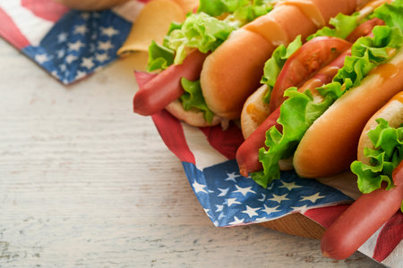 4th of July American Independence Day traditional picnic food. Hot dog with potato chips and cocktail, American flags and symbols of USA Patriotic picnic holiday on white wooden background. top viewの写真素材