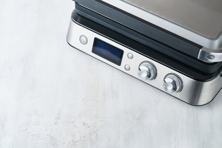 electric grill. Modern kitchen portable grill tool for modern kitchen for grilling meat, vegetables and snacks for dinner or party on light gray background. Place for text or advertisement. Mock up.の写真素材
