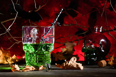 Halloween bloody cocktail. Halloween green cocktail glass goblet for Halloween and bottle form skull on dark backgrounds. Halloween party with candy eyes, bats, spiders. Dia de los Muertos. Clous up.の写真素材