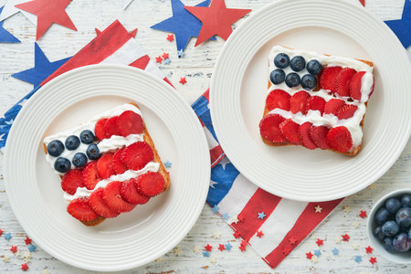 4th of July American Independence Day food. American flag sandwich with strawberries, blueberries, whipped sweet cream, soft cheese on toast bread. Independence or Patriotic Day breakfast idea Mock upの写真素材