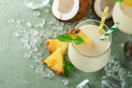 Pina Colada. Traditional caribbean cocktail from rum, pineapple juice and Coconut cream with tropical fruits and bar tools on fresh green background. Summer tropical cocktail and relaxation concept.の写真素材
