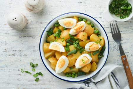 Traditional Potato salad with bacon and eggs in a white bowl. Picnic food concept. Bowl of warm potato salad. German Kartoffelsalat. top view.の写真素材