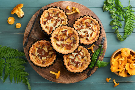 Savory hands pie with chanterelle mushrooms, cream and cheese on cutting board on rustic old wooden table background. Homemade tarts with seasonal chanterelle mushrooms. rustic style. top view.の写真素材