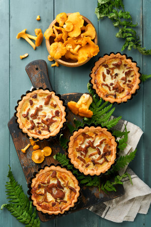 Savory hands pie with chanterelle mushrooms, cream and cheese on cutting board on rustic old wooden table background. Homemade tarts with seasonal chanterelle mushrooms. rustic style. top view.の写真素材