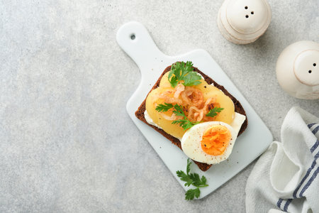 Open sandwich or smorrebrod with rye bread, herring, eggs, caramelized onions, parsley and cottage...