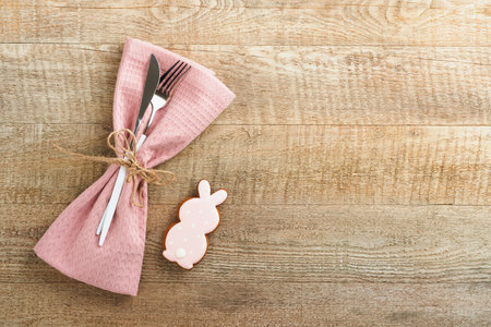 Easter brunch table setting. Spring Easter holiday concept with white, pink plate and napkin with decorative symbols holiday rabbit, eggs and bouquet of flowers on old wooden background. top view.の写真素材