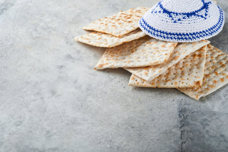 Passover celebration concept. Matzah, red kosher and walnut. Traditional ritual Jewish bread matzah, kippah and tallit on old concrete background. Passover food. Pesach Jewish holiday.の写真素材