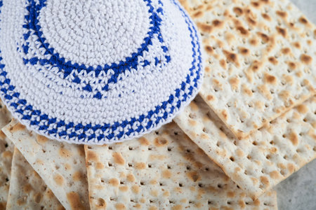 Passover celebration concept. Matzah, red kosher and walnut. Traditional ritual Jewish bread matzah, kippah and tallit on old concrete background. Passover food. Pesach Jewish holiday.の写真素材