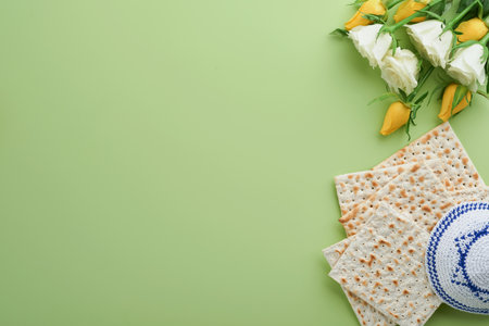 Passover celebration concept. Matzah, kosher red wine, walnut and spring white and yellow rose flowers. Traditional ritual Jewish bread on light green background. Passover food. Pesach Jewish holiday.の写真素材