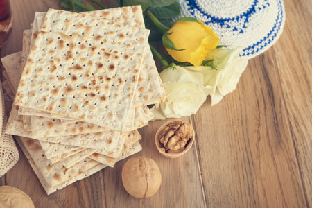 Passover celebration concept. Matzah, red kosher and walnut. Traditional ritual Jewish bread matzah, kippah and tallit on old wooden background. Passover food. Pesach Jewish holiday. toned image.の写真素材