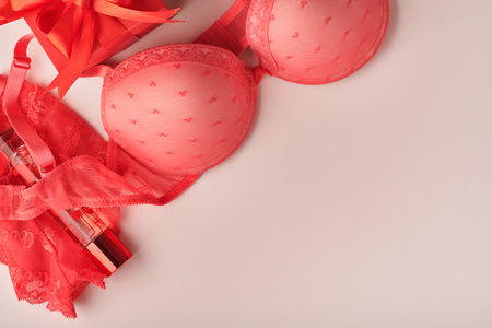 Red sexy bra and panties on pink background. Women sexy underwear set with roses and perfume. Gift Idea for Womens Day or Valentines day with copy space. Surprise for men or for him. top view.の写真素材