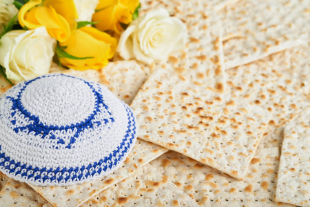 Passover celebration concept. Matzah, red kosher, white and yellow roses and walnut. Traditional ritual Jewish bread matzah, kippah and tallit on old background. Passover food. Pesach Jewish holiday.の写真素材