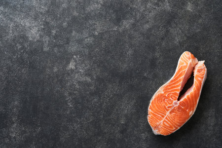 Salmon. Raw salmon steak. Fresh raw salmon fish with cooking ingredients, herbs and lemon prepared for grilled baking on black background. Health food. top view. copyspace.の写真素材