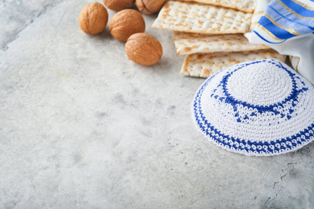 Passover celebration concept. Matzah, red kosher and walnut. Traditional ritual Jewish bread matzah, kippah and tallit on old concrete background. Passover food. Pesach Jewish holiday.の写真素材
