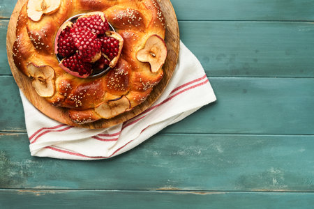 Jewish Holidays - Rosh Hashanah or Rosh Hashanah. Pomegranate, apples, honey and round challah on old wooden blue table background. Jewish autumn celebration. Shana Tova. Yom kippur concept. top viewの素材 [FY310211056220]