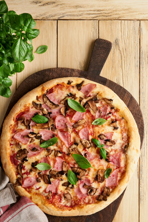 Pizza. Traditional Bacon pizza with ham, mushrooms, pickled cucumber and cheese and cooking ingredients tomatoes basil on wooden table backgrounds. Italian Traditional food. Top view. Mock up.の写真素材