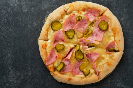 Pizza. Traditional Bacon pizza with ham, mushrooms, pickled cucumber and cheese and cooking ingredients tomatoes basil on wooden table backgrounds. Italian Traditional food. Top view. Mock up.の写真素材