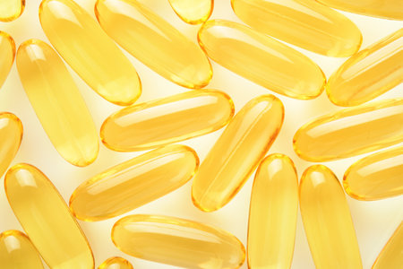 Capsules. Yellow pills isolated on white. Close up capsules with Vitamin D, E or Omega 3,6,9 fatty acids. Food supplement oil filled fish oil. Natural supplements for healthy good life concept. Bannerの写真素材