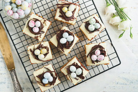 Easter carrot cake bars decorated with chocolate nest and chocolate candy eggs blossoming cherry or...