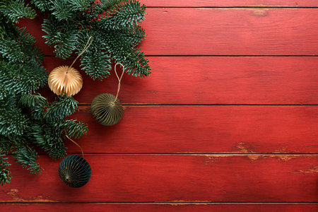 Christmas composition. Christmas fir tree branches with pine cones and papers rustic balls on wooden red rustic background. Christmas greeting card. Flat lay, top view. Copy space. Banner backdrop.の写真素材