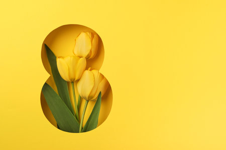 8 March greeting card. Paper cut Eight made of yellow background and fresh spring flowers bouquet of yellow tulips. Greeting card for Womens Day on March 8 Flat lay top view. International Women's dayの写真素材